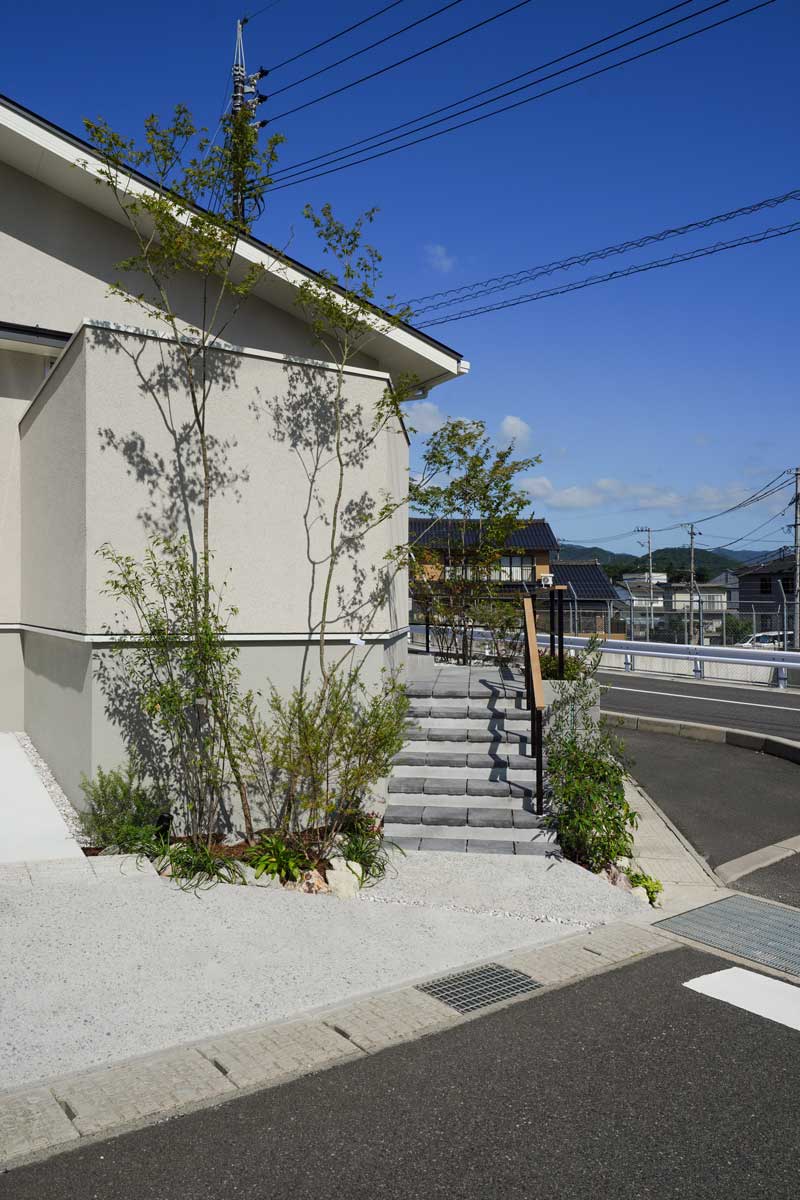 白い外壁と緑が織りなす、自然と調和した外構デザイン